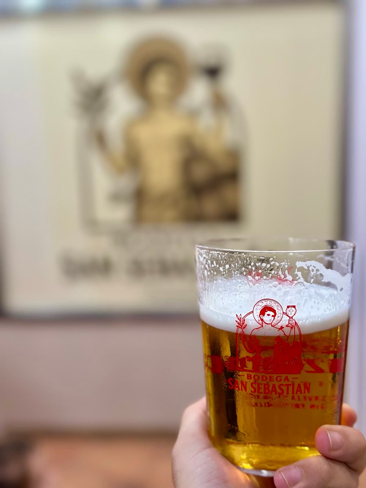 Caña de Cruzcampo en el vaso de la casa, con el santo al fondo