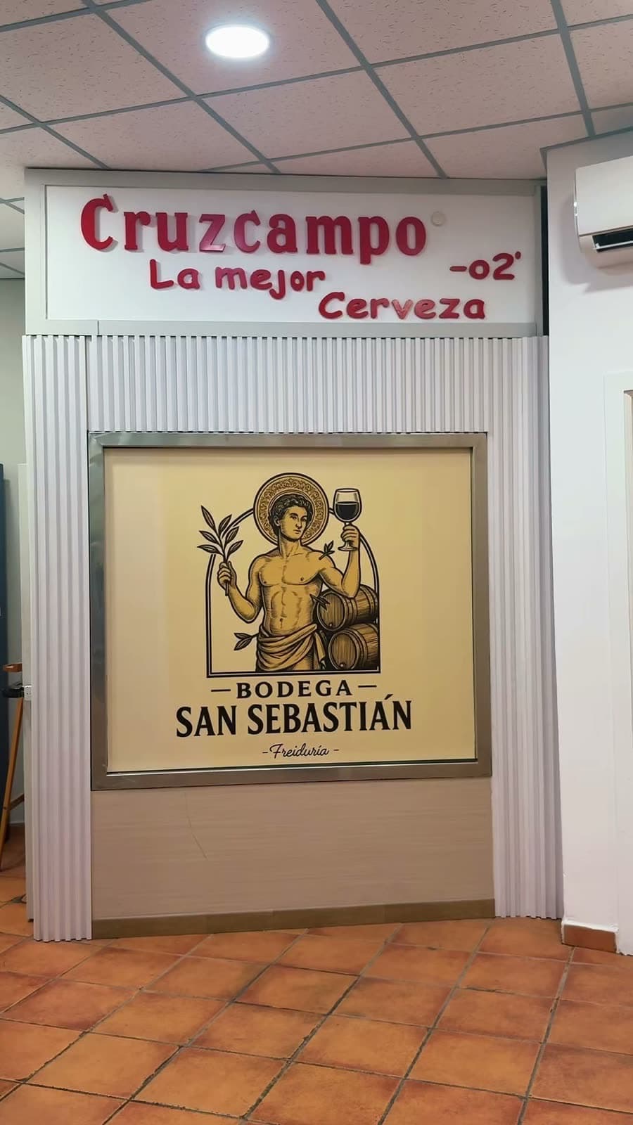 El salón: el cuadro de San Sebastián bajo el rótulo de Cruzcampo
