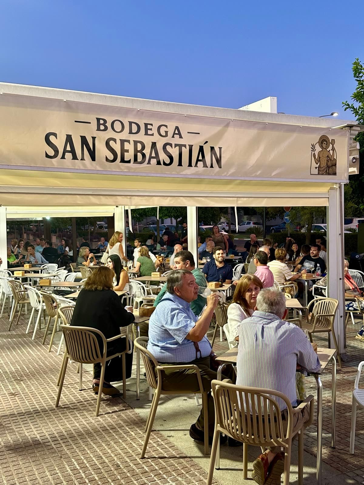 La terraza llena bajo el toldo con el nombre de la casa